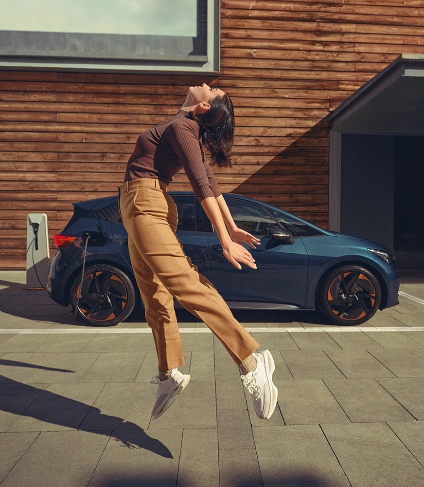 woman-jumping-cupra-Born-aurora-blue-colour-charging